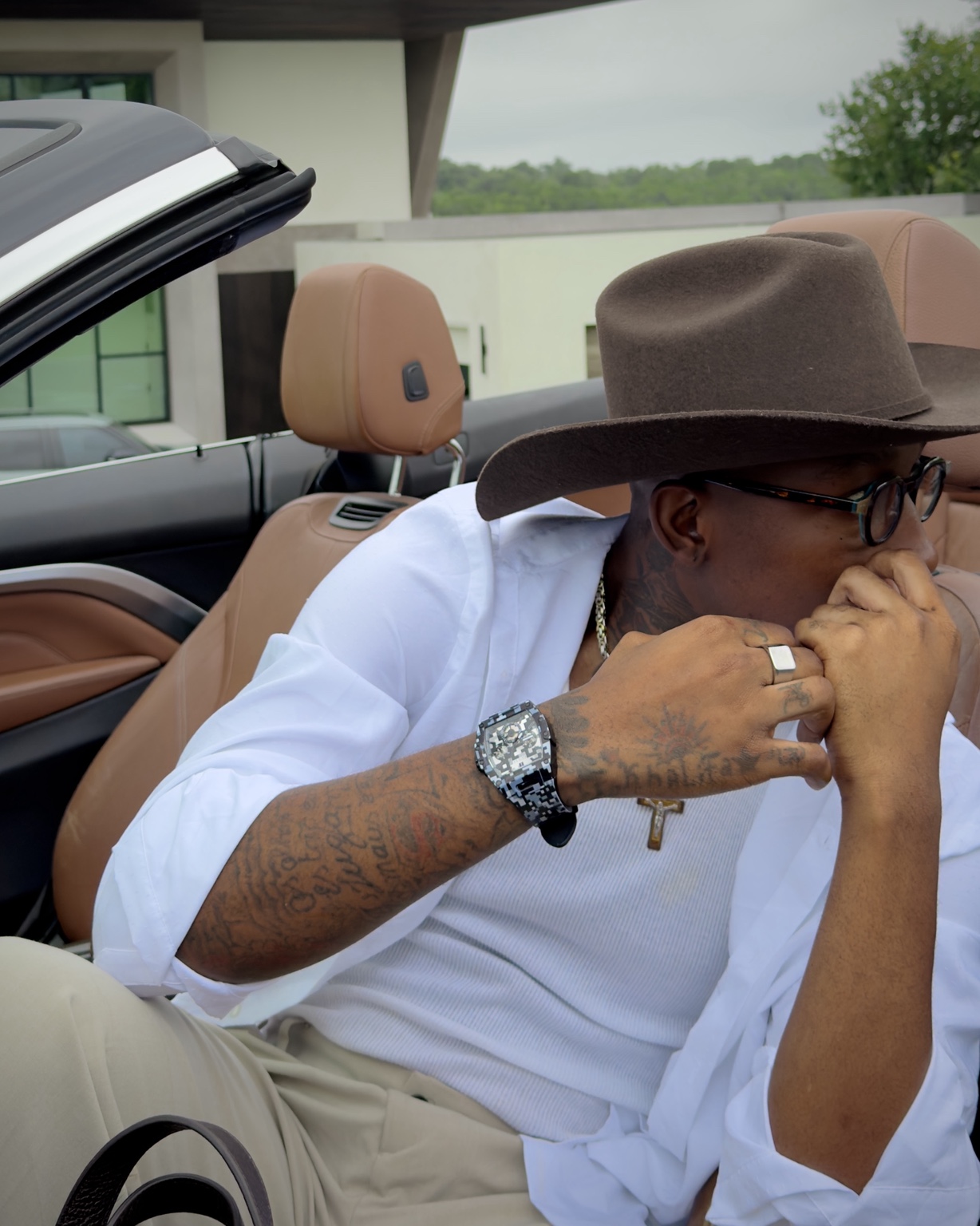 Claudio Conde wearing a white shirt and brown hat in a convertible