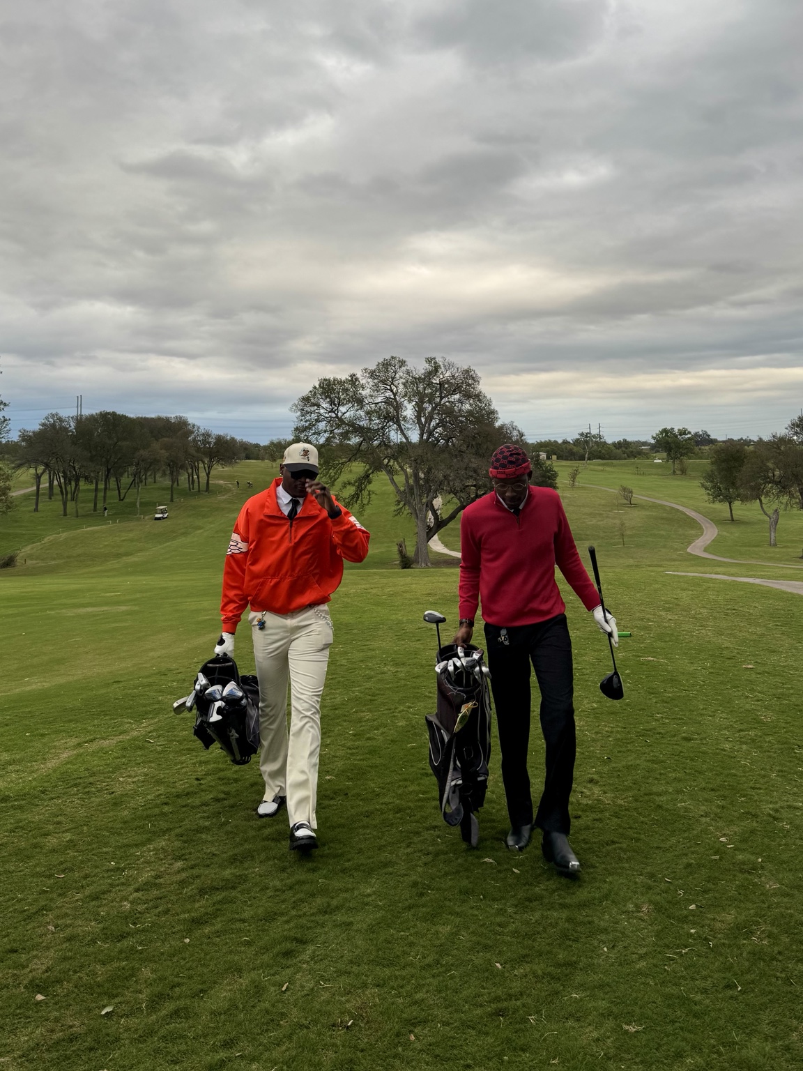 Claudio Conde and a companion carrying golf bags on a golf course