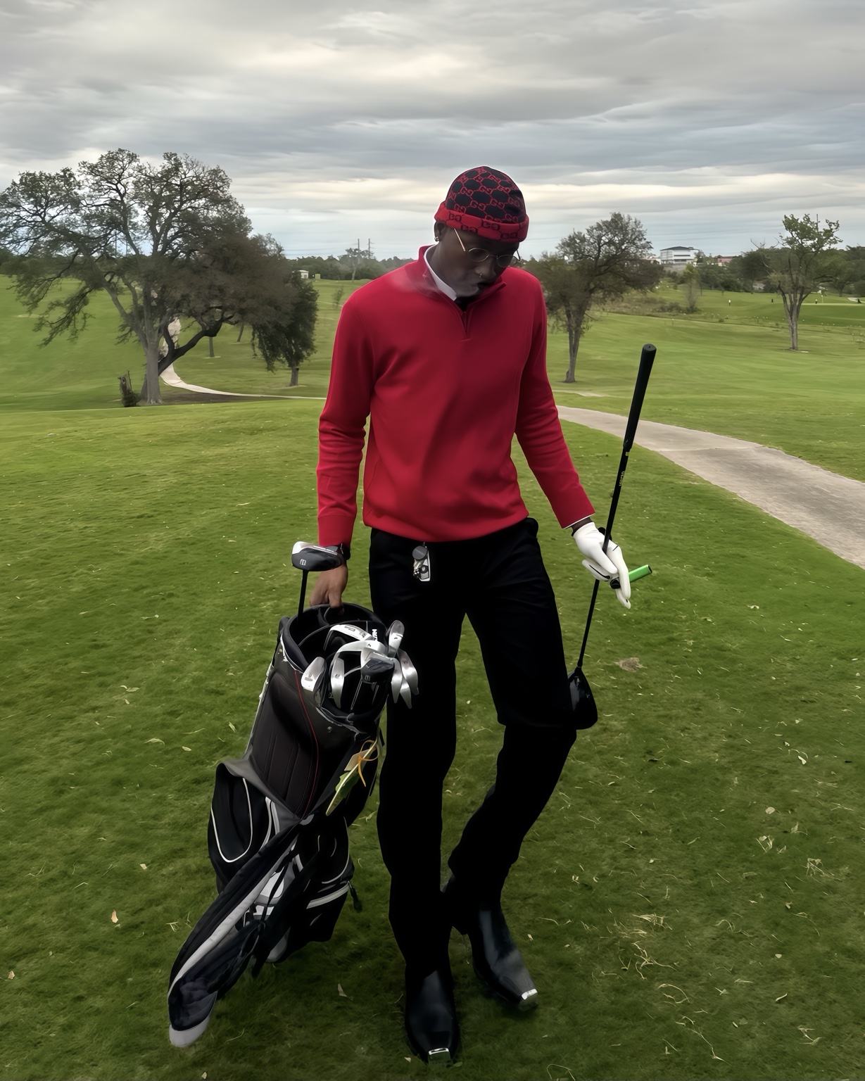 Claudio Conde wearing a red sweater and carrying a golf bag on the course